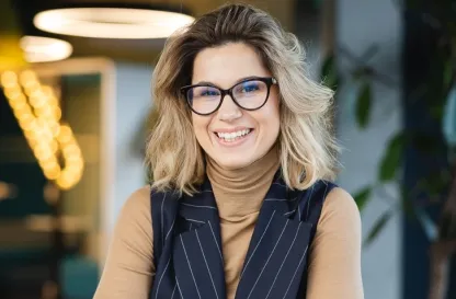 Aktualności | Uniwersytet WSB Merito w Poznaniu: Uśmiechnięta kobieta w okularach przy biurku