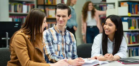 Studia jednolite magisterskie w Poznaniu | Uniwersytet WSB Merito w Poznaniu: trójka studentów drugiego stopnia, na uczelni, siedzą przy biurku