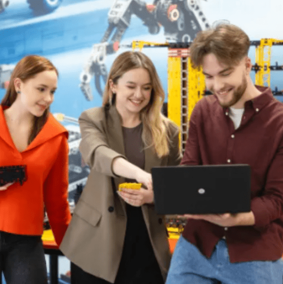 Fuzje i przejęcia | Studia I stopnia w Poznaniu | Uniwersytet WSB Merito w Poznaniu: trójka studentów, uśmiechnięta, rozwiązują zadanie na laptopie