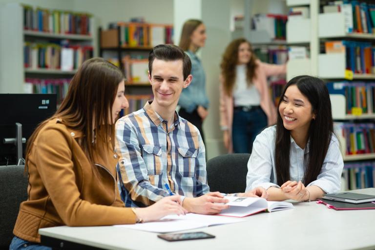Studia jednolite magisterskie w Poznaniu | Uniwersytet WSB Merito w Poznaniu: trójka studentów drugiego stopnia, na uczelni, siedzą przy biurku