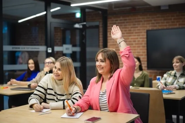 Współczesne media w marketingu | Studia I stopnia w Poznaniu | Uniwersytet WSB Merito w Poznaniu: Studentki biorą aktywny udział w zajęciach, jedna z nich z uśmiechem podnosi rękę