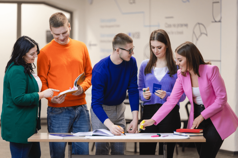 Szkolenia i kursy w Poznaniu | Uniwersytet WSB Merito w Poznaniu: Grupa studentów wspólnie pracuje nad materiałami przy stole