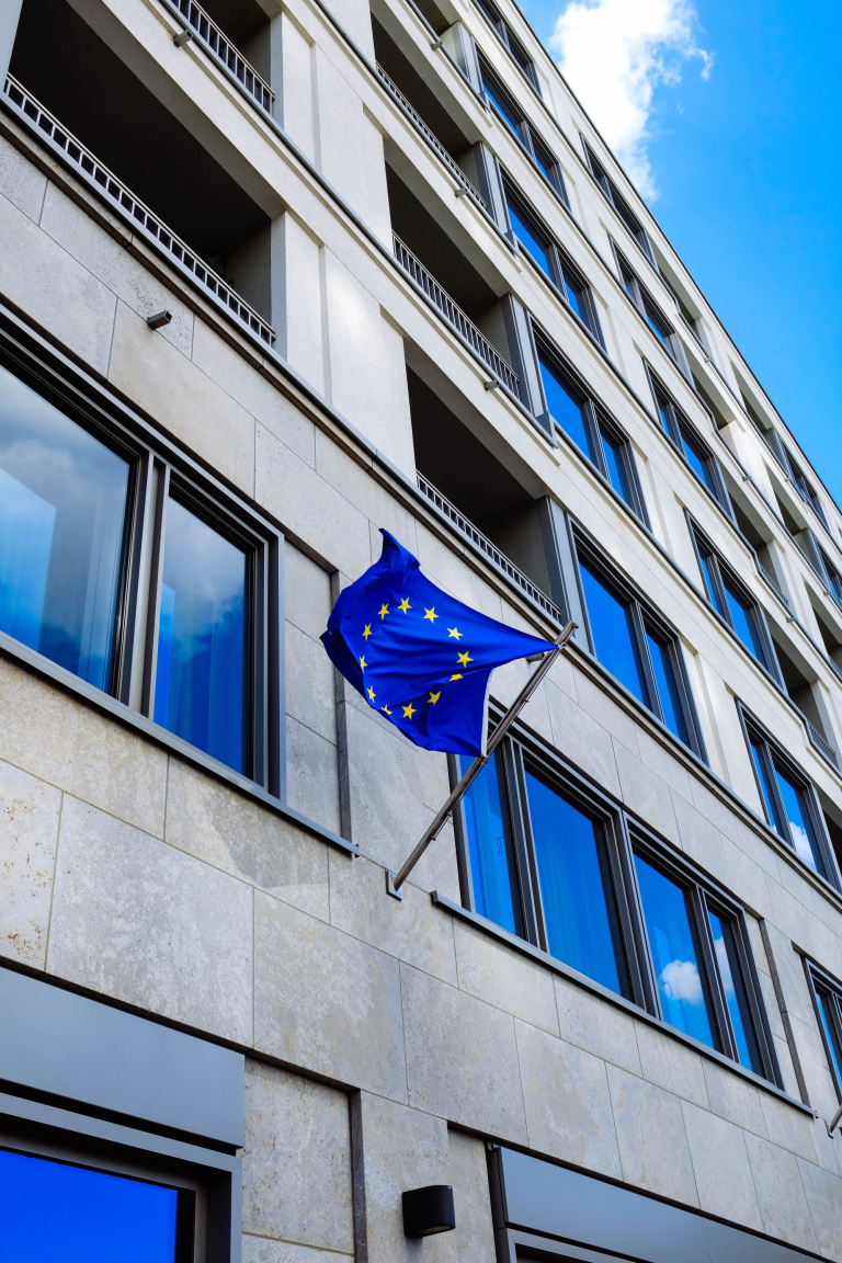 Konferencja "Silne regiony, odporna Europa – bezpieczeństwo społeczeństw, instytucji i gospodarki" | Uniwersytet WSB Merito w Poznaniu: flaga europy na tle budynku