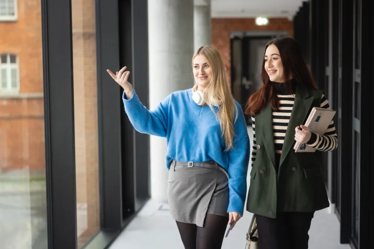 Cyfrowe procesy biznesowe | Studia I stopnia w Poznaniu | Uniwersytet WSB Merito w Poznaniu: Dwie studentki, kolorowo ubrane spacerują po korytarzu uczelni WSB Merito w Poznaniu 