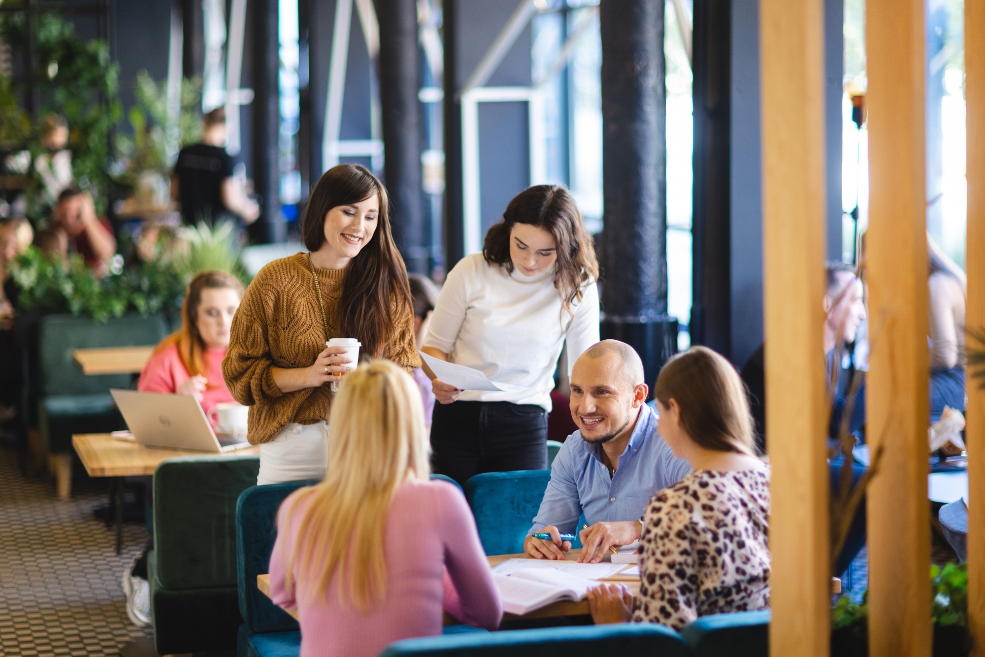 Grupa ludzi rozmawiająca przy biurkach