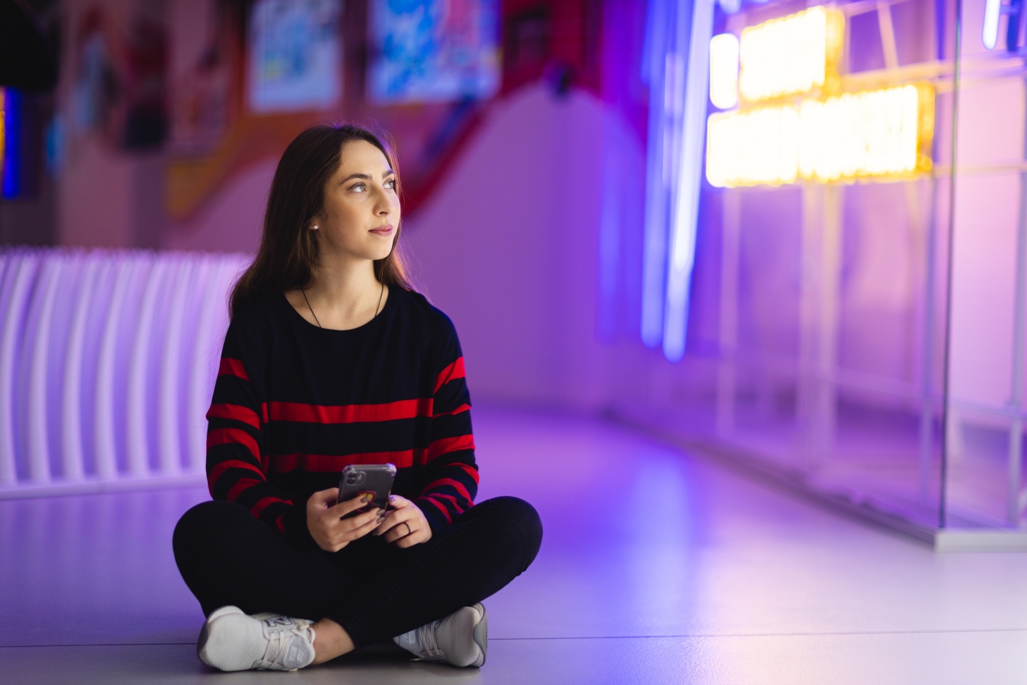 Dziewczyna siedząca "po turecku" w jaskrawej sali