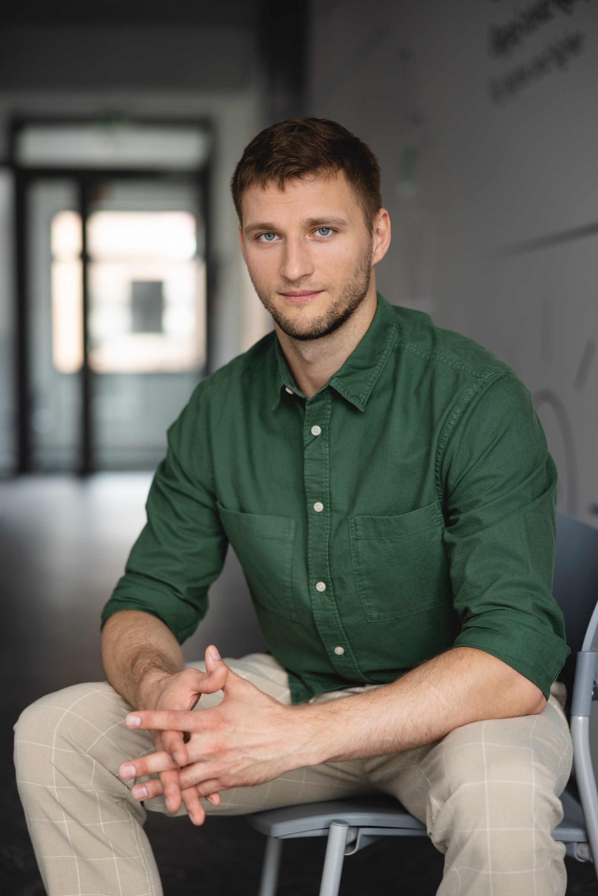 Mężczyzna w zielonej koszuli z rękoma opartymi o kolana