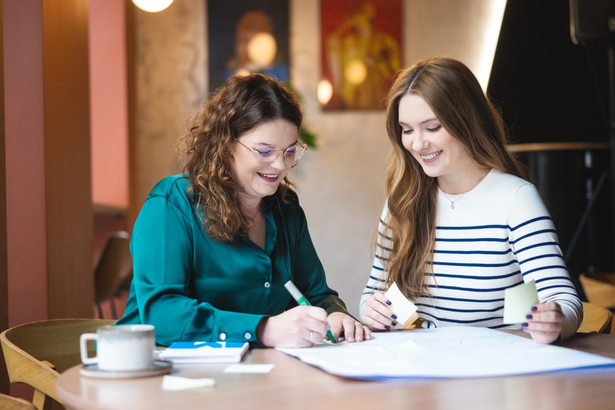 Dwie kobiety rozmawiające i pracujące przy stole