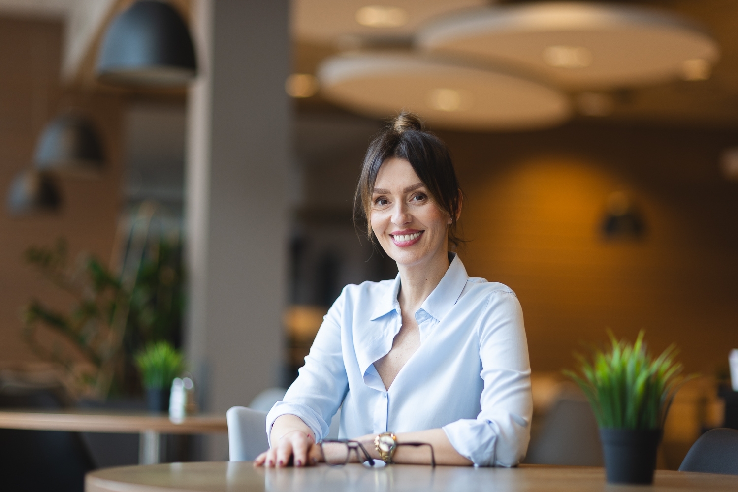 Kobieta w jasnej koszuli siedząca przy stole