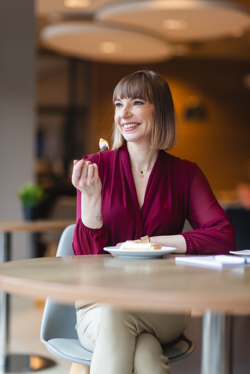 Kobieta siedząca prawdopodobnie w kawiarni, jedząca ciasto