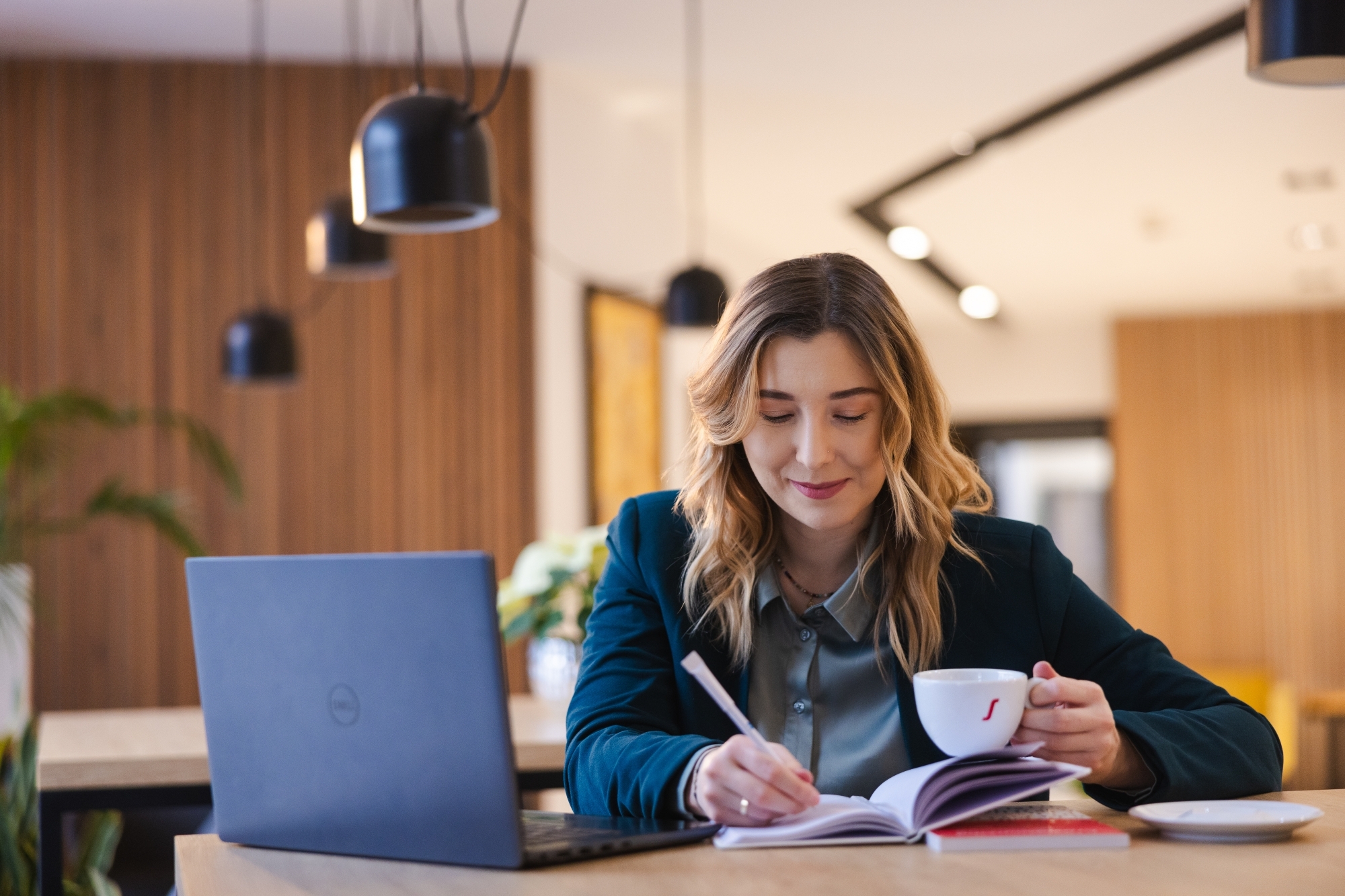 Dziewczyna pracująca przy laptopie, trzymająca filiżankę kawy