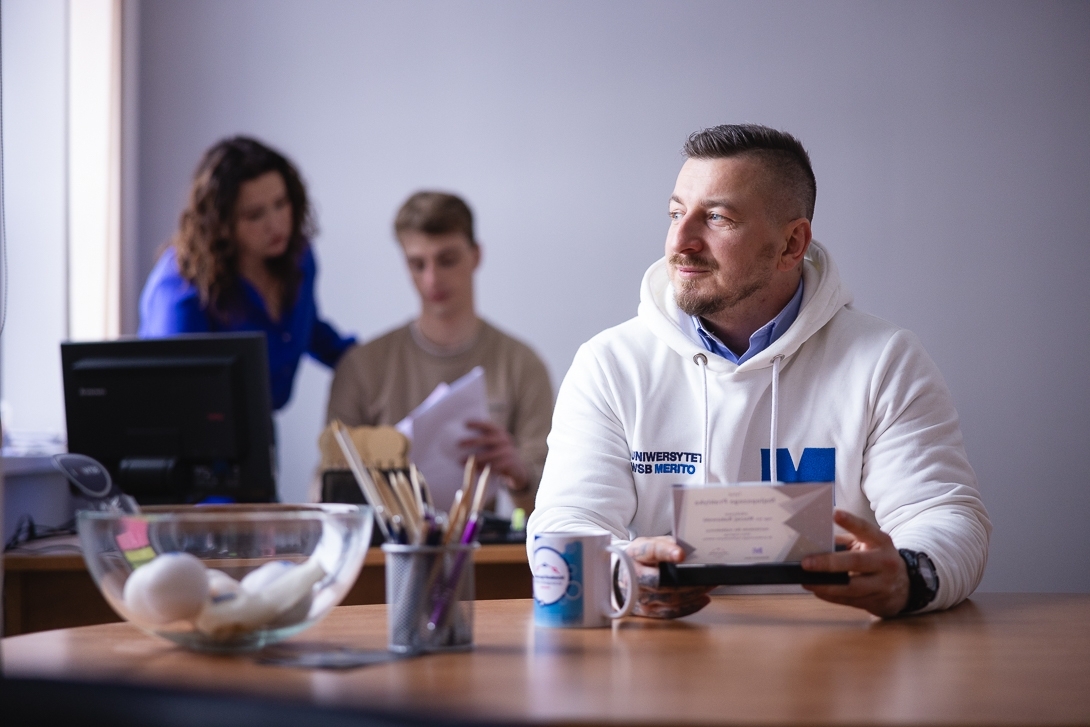 Mężczyzna siedzący przy biurku, patrzący w stronę okna