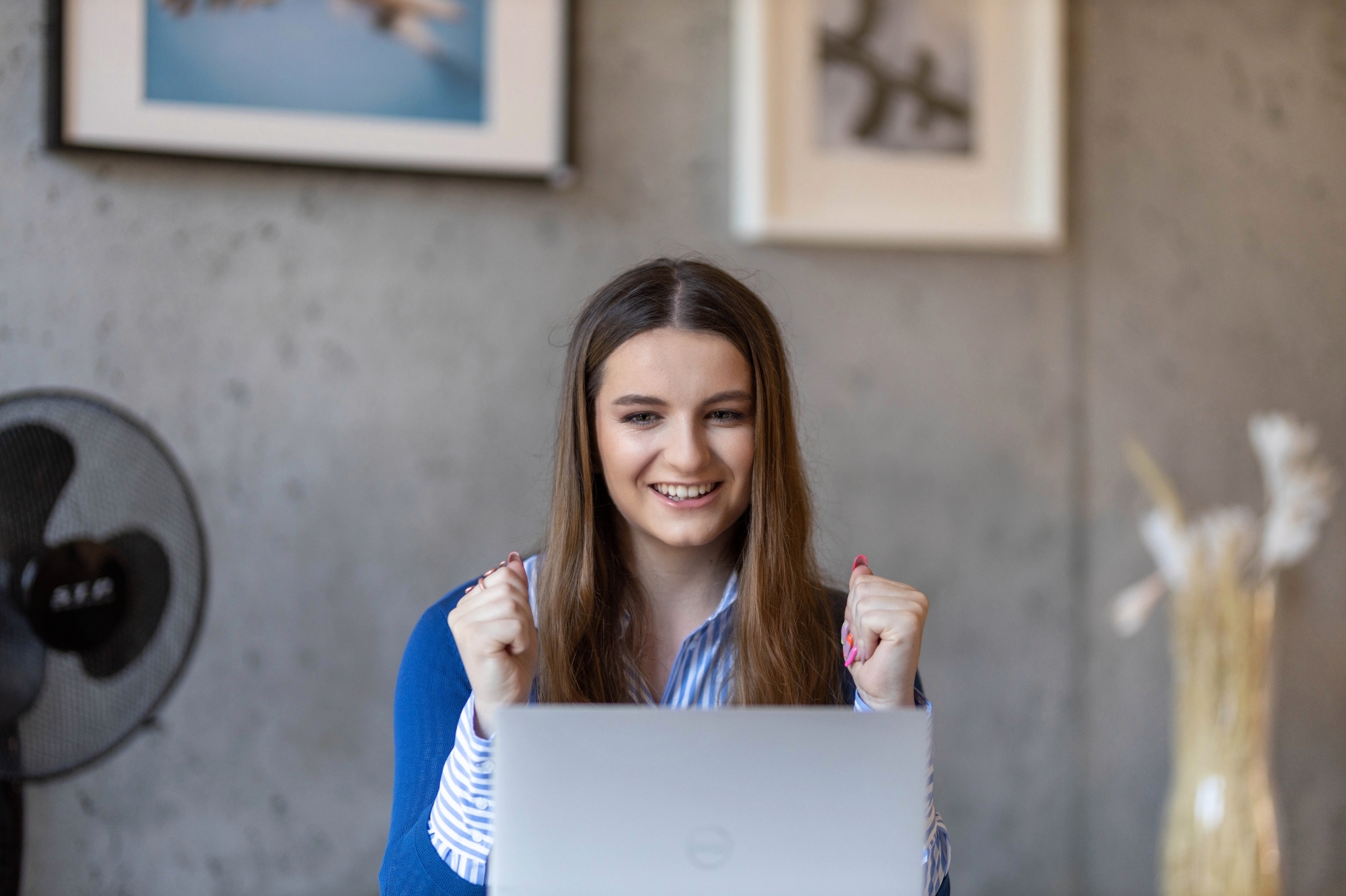 Młoda dziewczyna okazująca radość spoglądajać w ekran laptopa