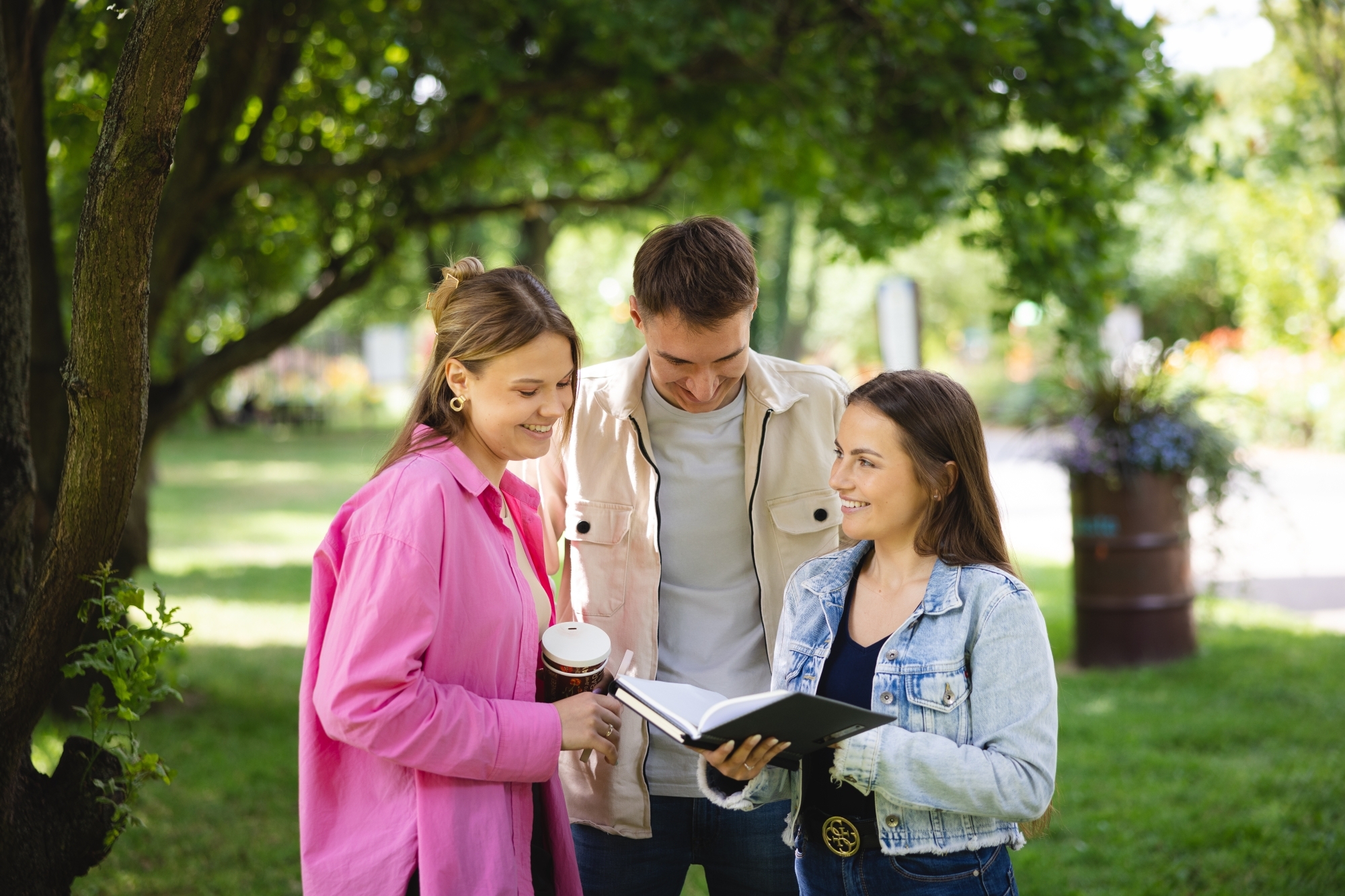 Trzy osoby patrzące w książkę w parku