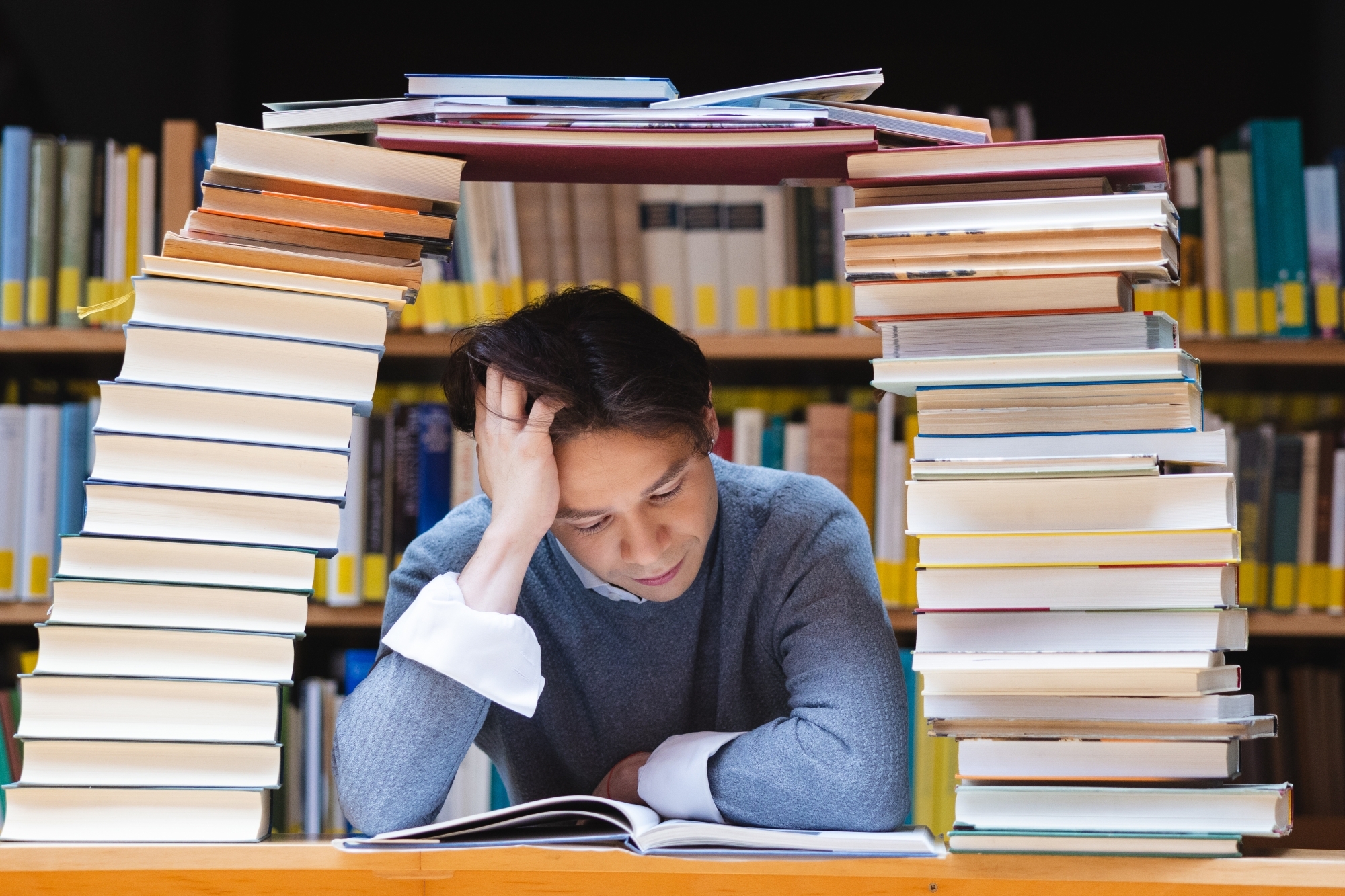Mężczyzna pod stosem książek