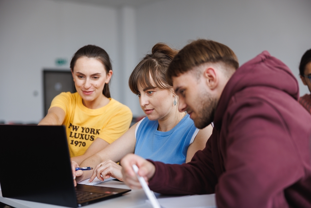 Trzy osoby siedzące przy laptopie
