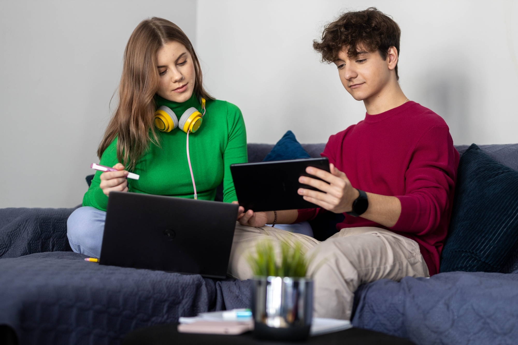 Dwoje młodych ludzi siedzących na kanapie pracujących.