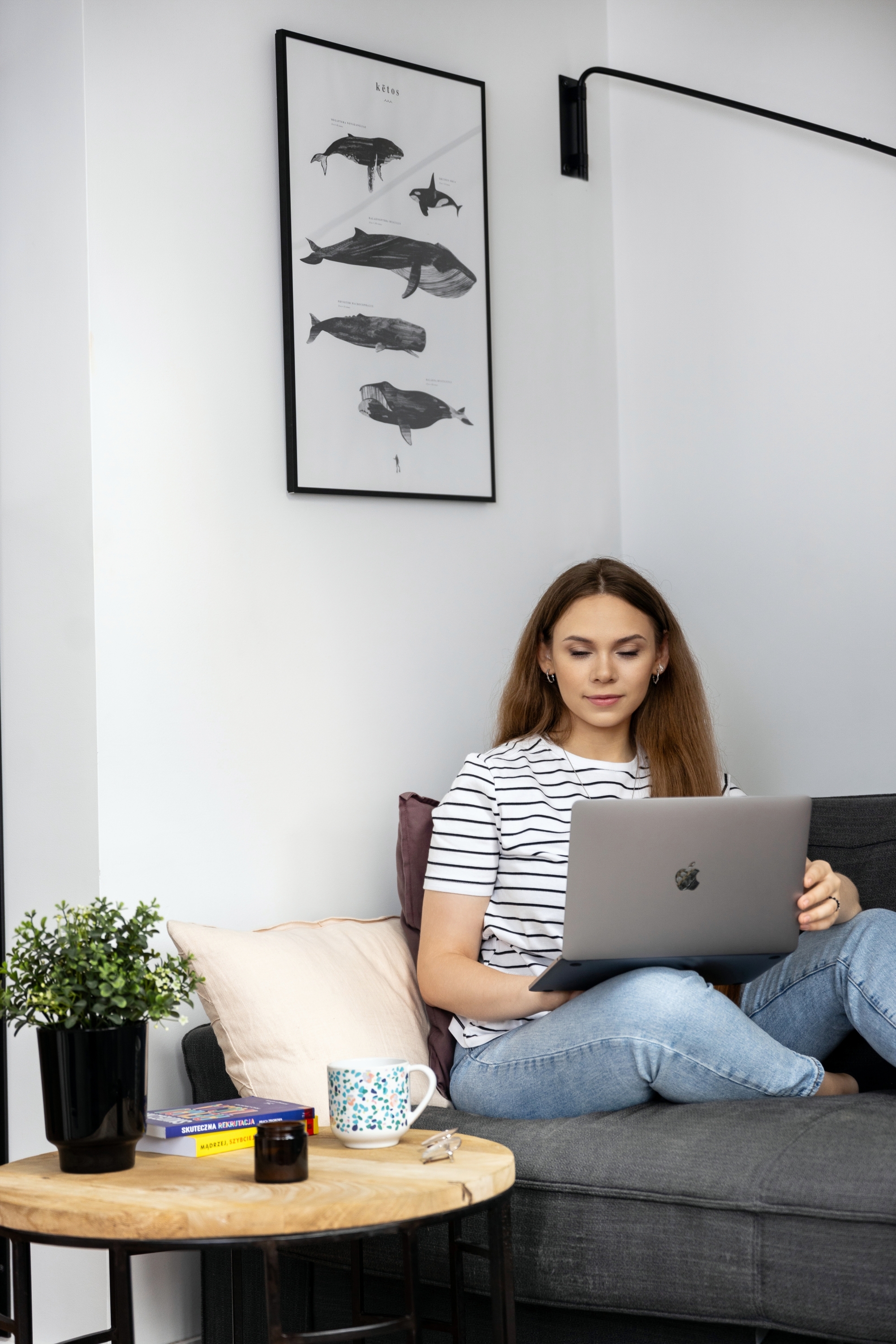 Dziewczyna pracująca przy laptopie siedząc na kanapie