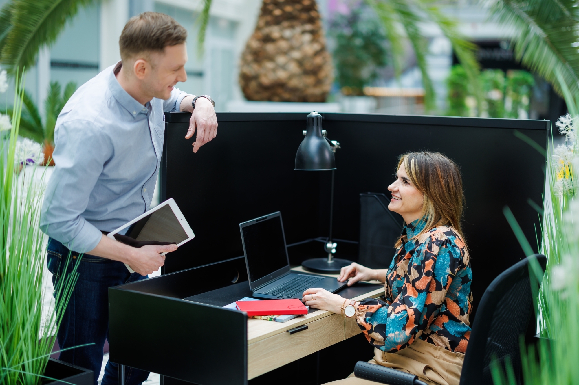 Dwie osoby rozmawiające, mężczyzna oparty o ściankę