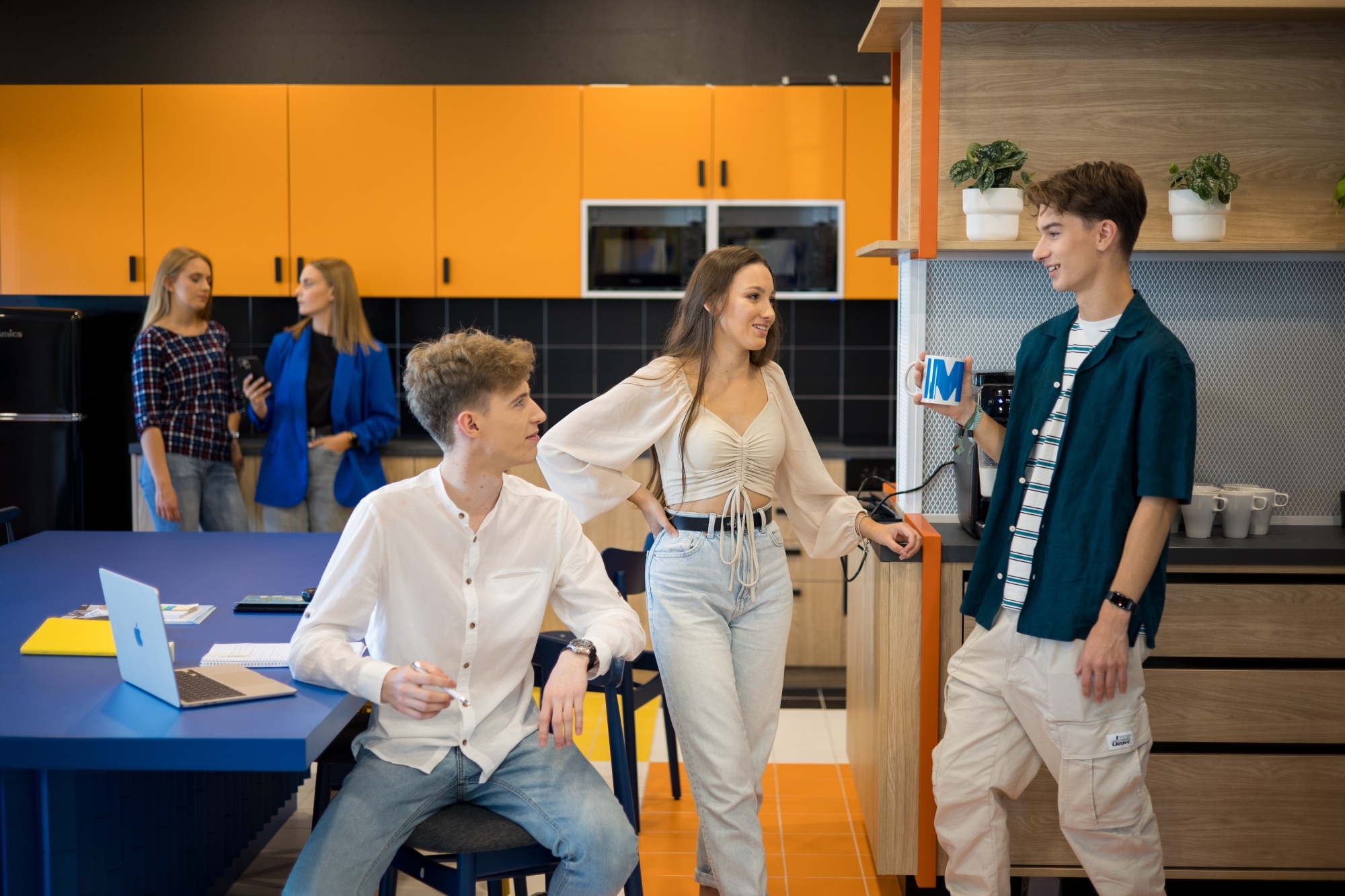 Troje młodych ludzi rozmawiających w kuchni w biurze