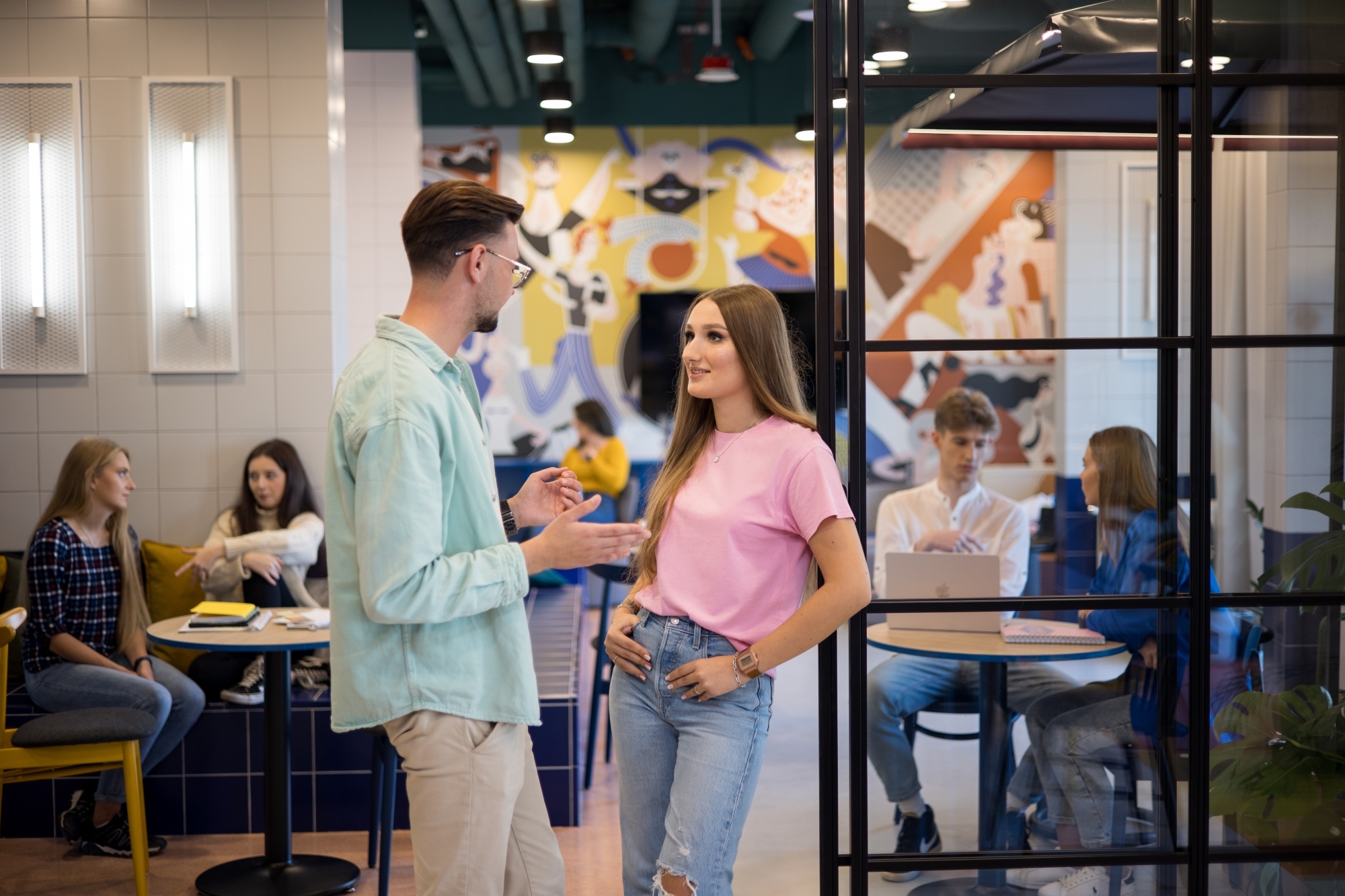 Dwoje młodych ludzi rozmawiających w biurze