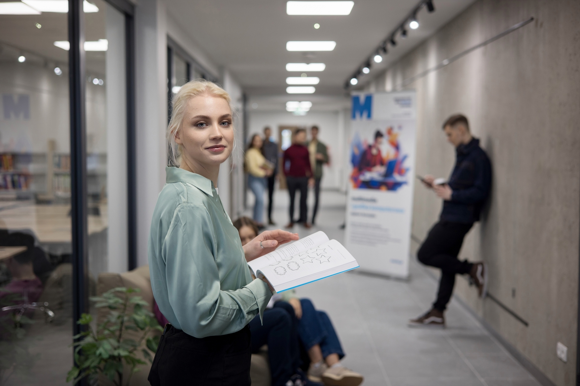 Studentka na korytarzu uczelni z książką w ręku
