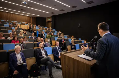 Sustainable and Socially Responsible Development in the Network of Socioeconomic Relations | Uniwersytet WSB Merito: Widok sali konferencyjnej oraz prelegenta przemawiającego przy pulpicie