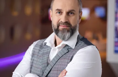 Blog "Okiem Praktyków" | Uniwersytet WSB Merito: Mężczyzna w średnim wieku stojący z założonymi rękami