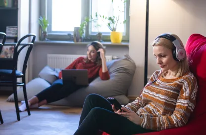 Blog "Okiem Praktyków" | Uniwersytet WSB Merito: Dwie osoby na zdjęciu, jedna z przodu czytająca książkę, druga siedząca w tle