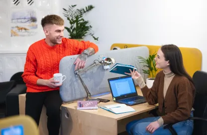 Poradniki - dzielimy się wiedzą | Uniwersytet WSB Merito: Dwoje ludzi rozmawiających przy biurku