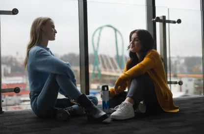 Blog "Okiem Praktyków" | Uniwersytet WSB Merito: Dwie dziewczyny prowadzące rozmowę siedząc przy oknie