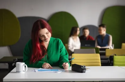 Poradniki - dzielimy się wiedzą | Uniwersytet WSB Merito: Grafika_główna_kobieta_pisząca_w_zeszycie