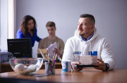 Poradniki - dzielimy się wiedzą | Uniwersytet WSB Merito: Mężczyzna siedzący przy biurku, patrzący w stronę okna