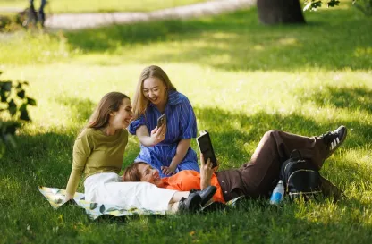 Poradniki - dzielimy się wiedzą | Uniwersytet WSB Merito: Trzy osoby siedzące na trawniku