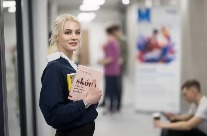 Blog "Okiem Praktyków" | Uniwersytet WSB Merito: Dziewczyna z książką wpatrująca się w obiektyw