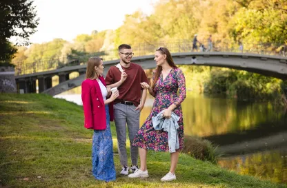 Poradniki - dzielimy się wiedzą | Uniwersytet WSB Merito: Troje młodych ludzi rozmawiających na świeżym powietrzu, w parku