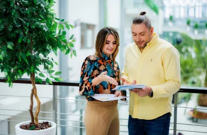 Poradniki - dzielimy się wiedzą | Uniwersytet WSB Merito: Para osób dyskutująca o dokumencie na korytarzu