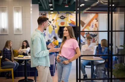 Poradniki - dzielimy się wiedzą | Uniwersytet WSB Merito: Dwoje młodych ludzi rozmawiających w biurze