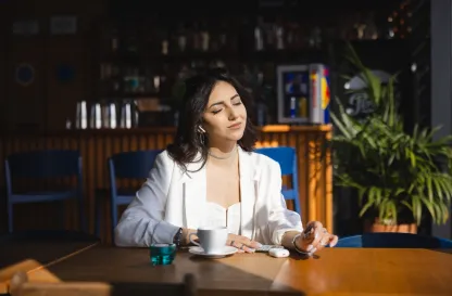 Blog "Okiem Praktyków" | Uniwersytet WSB Merito: Dziewczyna w kawiarni wystawiająca twarz do słońca