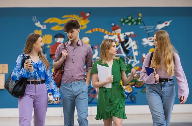 Blog "Okiem Praktyków" | Uniwersytet WSB Merito: Grupa studentów WSB Merito z plecakami na tle murala