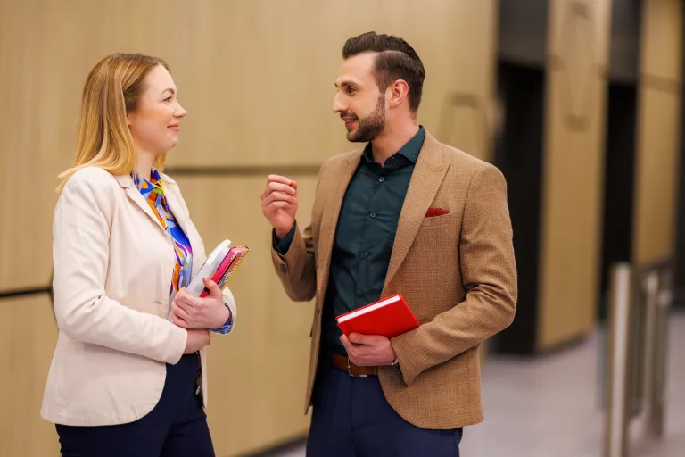Jak napisać podanie o pracę - poradnik v2 | Uniwersytet WSB Merito: Chłopak i dziewczyna rozmawiają na korytarzu