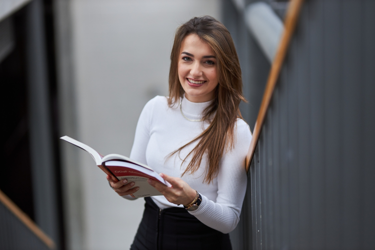 Wydawnictwa naukowe | Uniwersytet WSB Merito: Główna grafika: studentka z książką w ręku