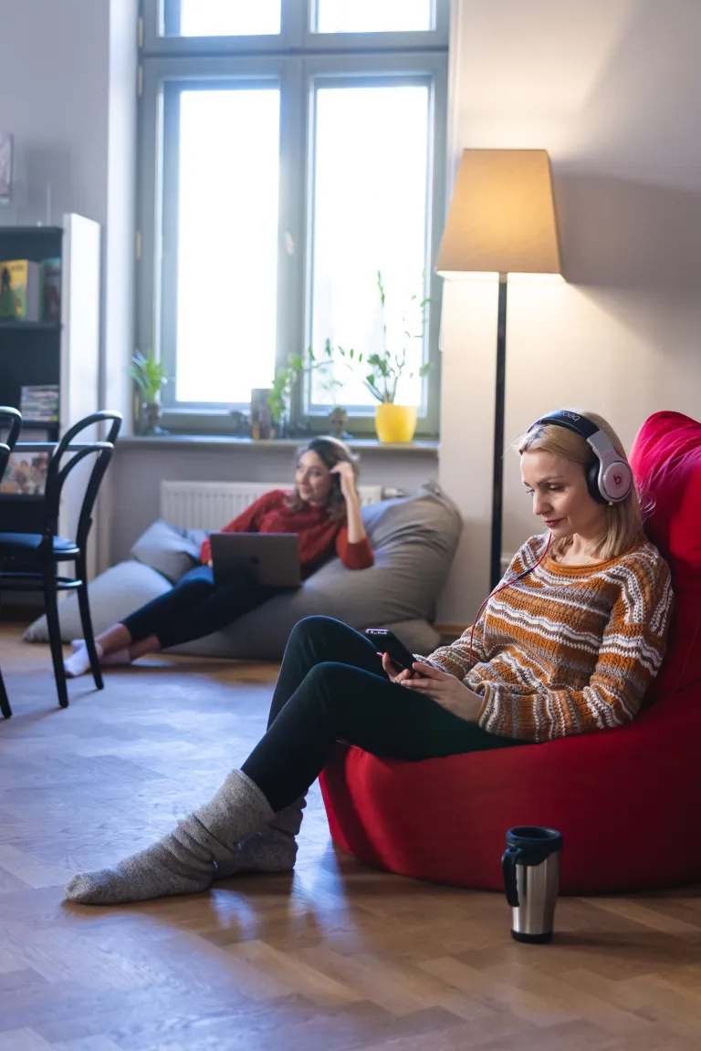 Odwlekasz naukę? Zacznij od… Digiteki! | Blog "okiem praktyków" | Uniwersytet WSB Merito: Dwie osoby na zdjęciu, jedna z przodu czytająca książkę, druga siedząca w tle