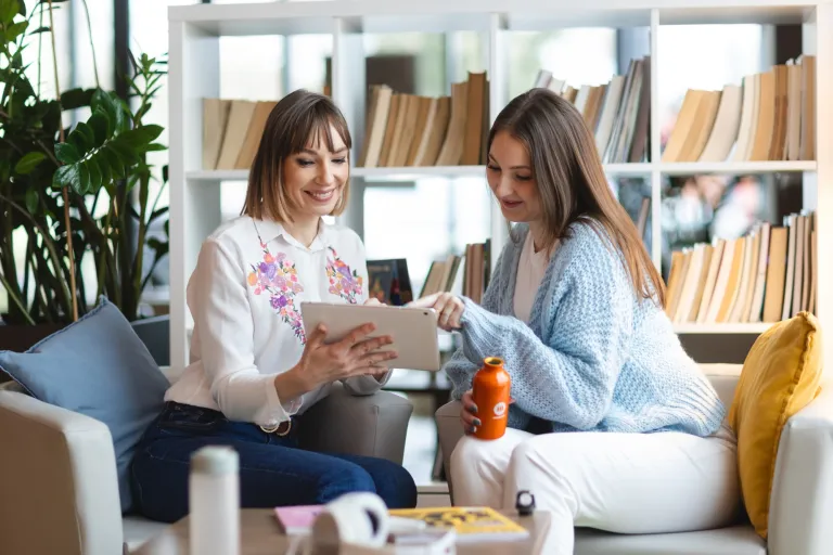 Wyniki wyszukiwania | Uniwersytet WSB Merito: Dwie kobiety siedzące w bibliotece, korzystające z tabletu