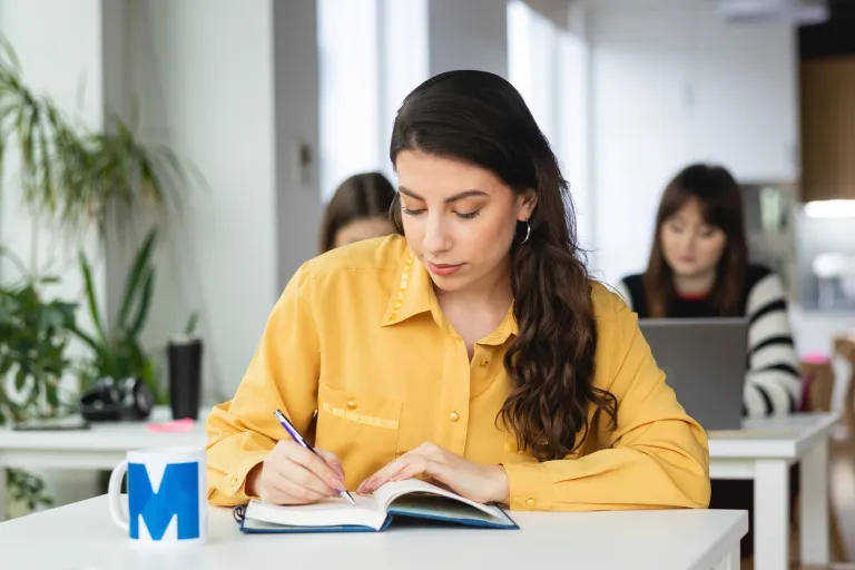 Software developer a software engineer - różnice | Uniwersytet WSB Merito: Dziewczyna uczestnicząca w zajęciach, robiąca notatki