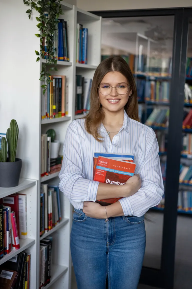 Studia logistyczne zdobywają coraz większą popularność. Sprawdź, co jest tego powodem | Uniwersytet WSB Merito: Dziewczyna trzymająca książki w dłoni