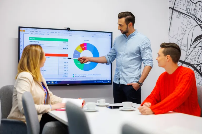 Jak inwestować w czasach kryzysu? | Blog "okiem praktyków" | Uniwersytet WSB Merito: Troje ludzi w biurze, pracujących przy tablicy