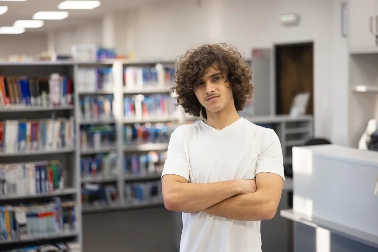 10 rad jak dobrze wypaść na rozmowie kwalifikacyjnej | Uniwersytet WSB Merito: Mężczyzna stojący w bibliotece