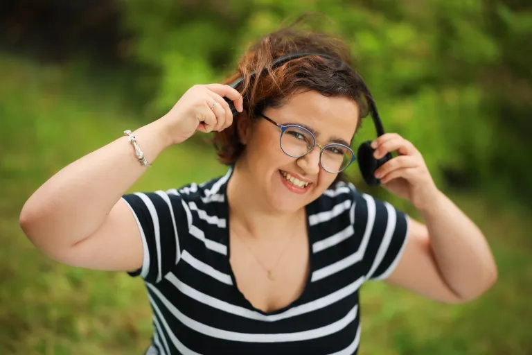 Jak efektywnie wykorzystać 3-miesięczne wakacje? | Uniwersytet WSB Merito: Uśmiechnięta dziewczyna nakładająca słuchawki