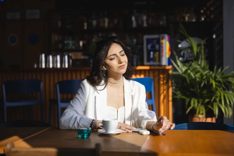 Witamina D a zimowy nastrój – czy naprawdę ma znaczenie | Blog "okiem praktyków" | Uniwersytet WSB Merito: Dziewczyna w kawiarni wystawiająca twarz do słońca